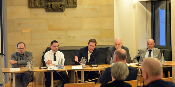 Foto von Personen die an einem Tisch sitzen und diskutieren.